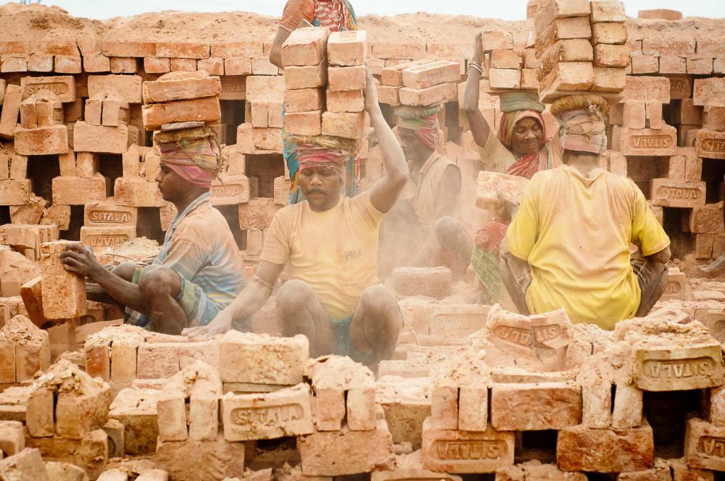 Workers load the bricks on their head and carry to the storage area